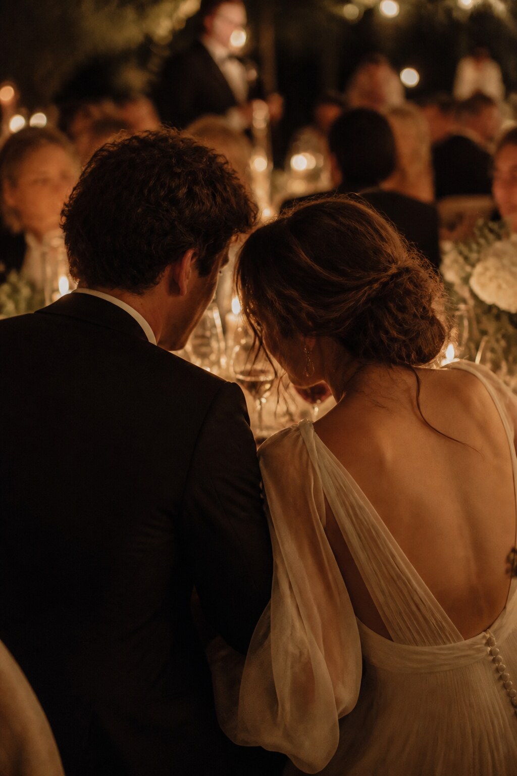 Mariés vus de dos pendant un dîner de mariage aux chandelles